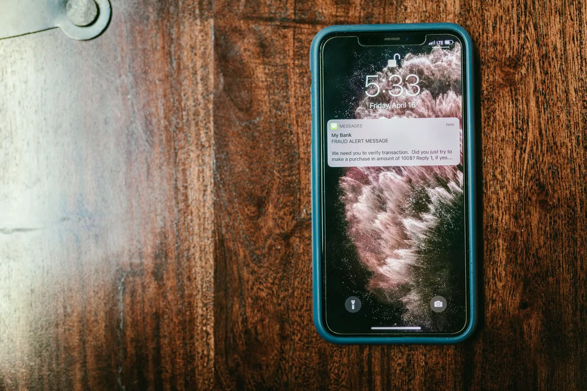 Telefon ekranında şüpheli bir mesaja bakan kişi