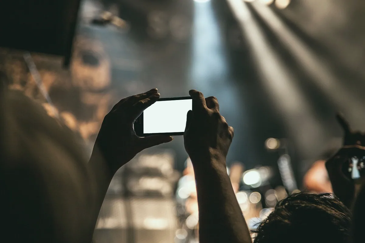 Halka ışık önünde telefonla video çeken kişi