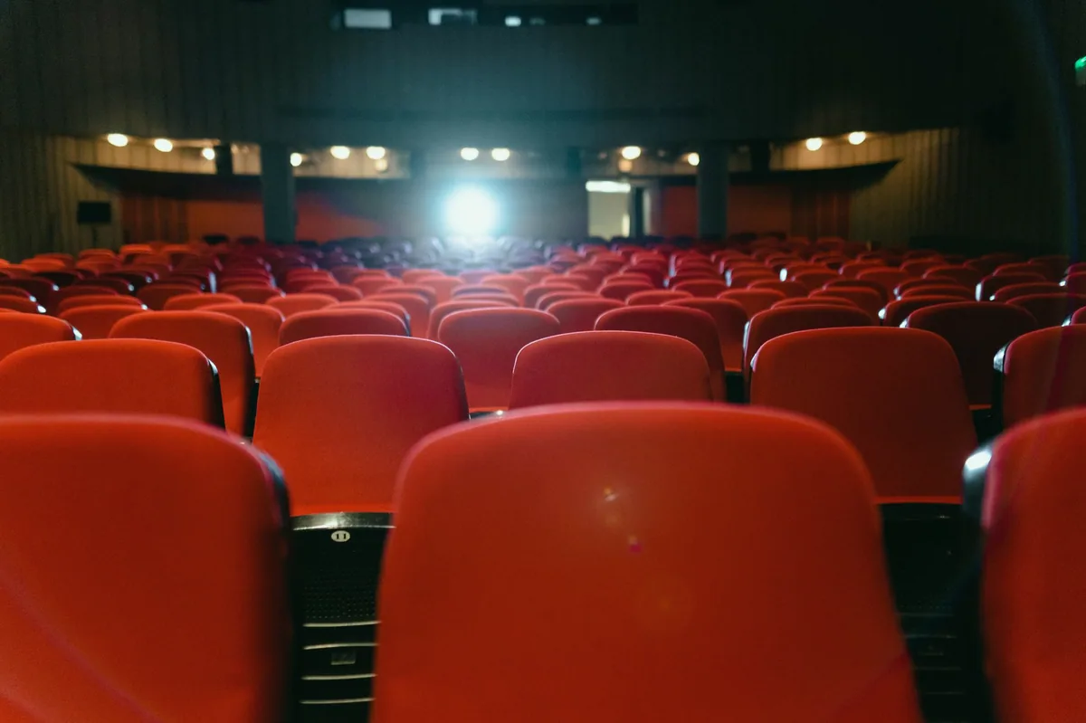 Karanlık sinema salonunda perdeye bakan koltuklar