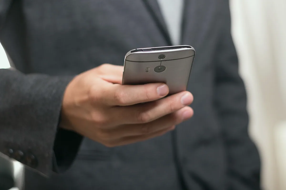 Akşam saatinde pencere kenarında telefonla mesajlaşan kişi