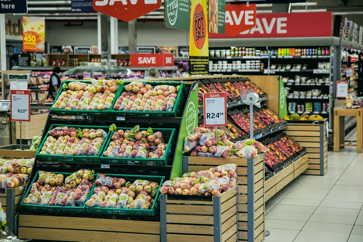 Market rafında birim fiyat etiketlerini karşılaştıran kişi