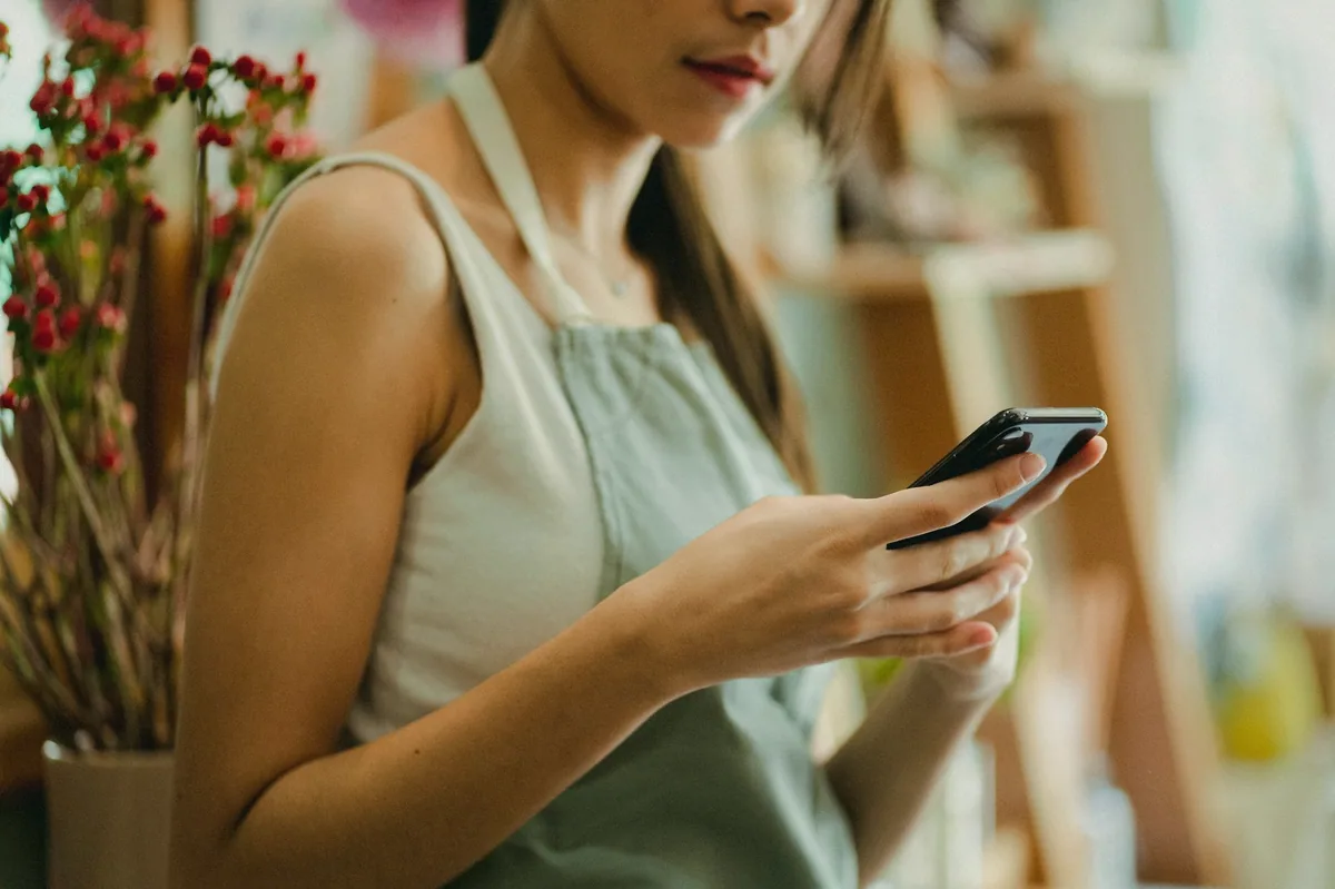 Küçük işletme sahibi telefondan müşteri mesajlarını okuyor