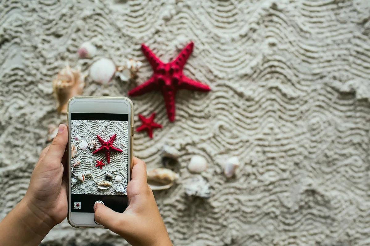 Telefon ekranında bir fotoğrafı büyüterek inceleyen el
