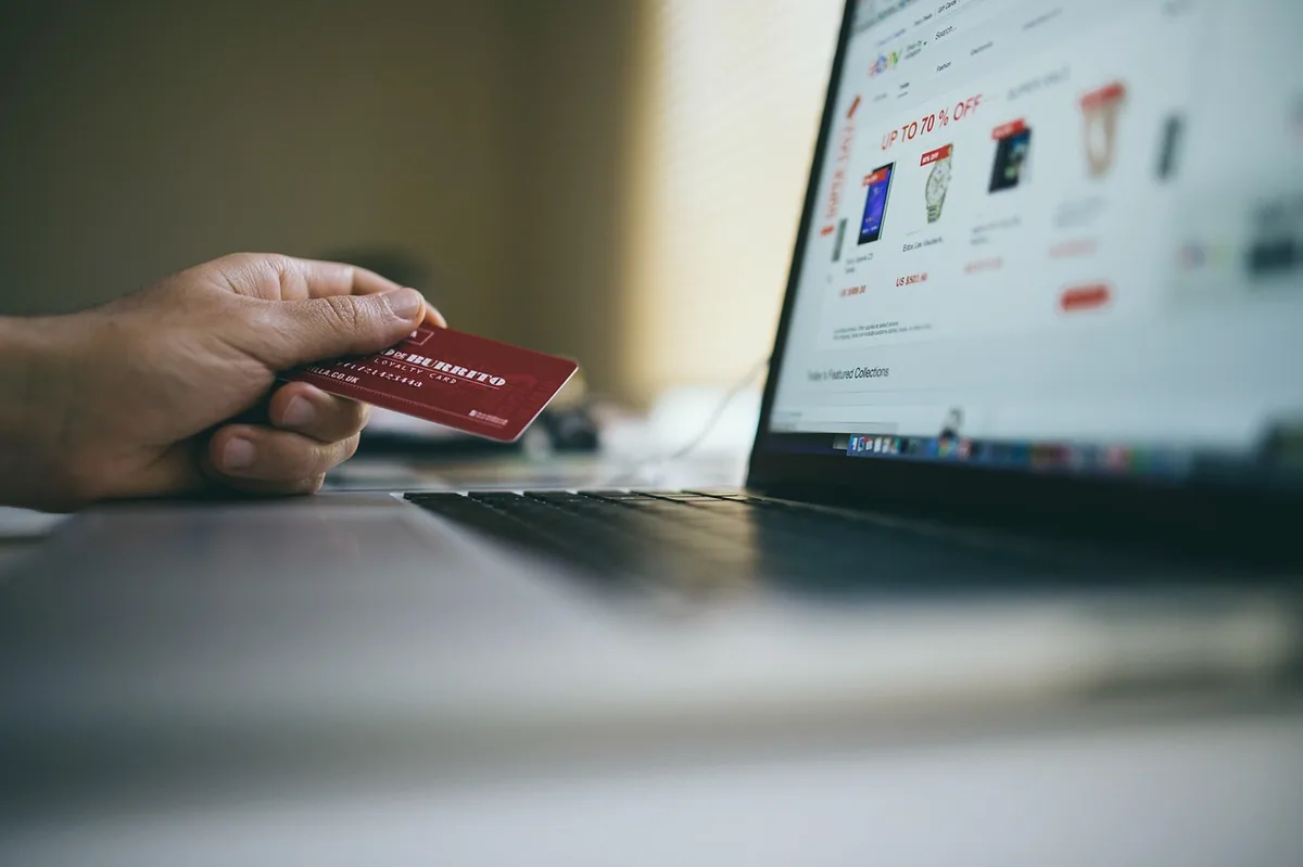 Dizüstü bilgisayarda internetten alışveriş yapan kişi