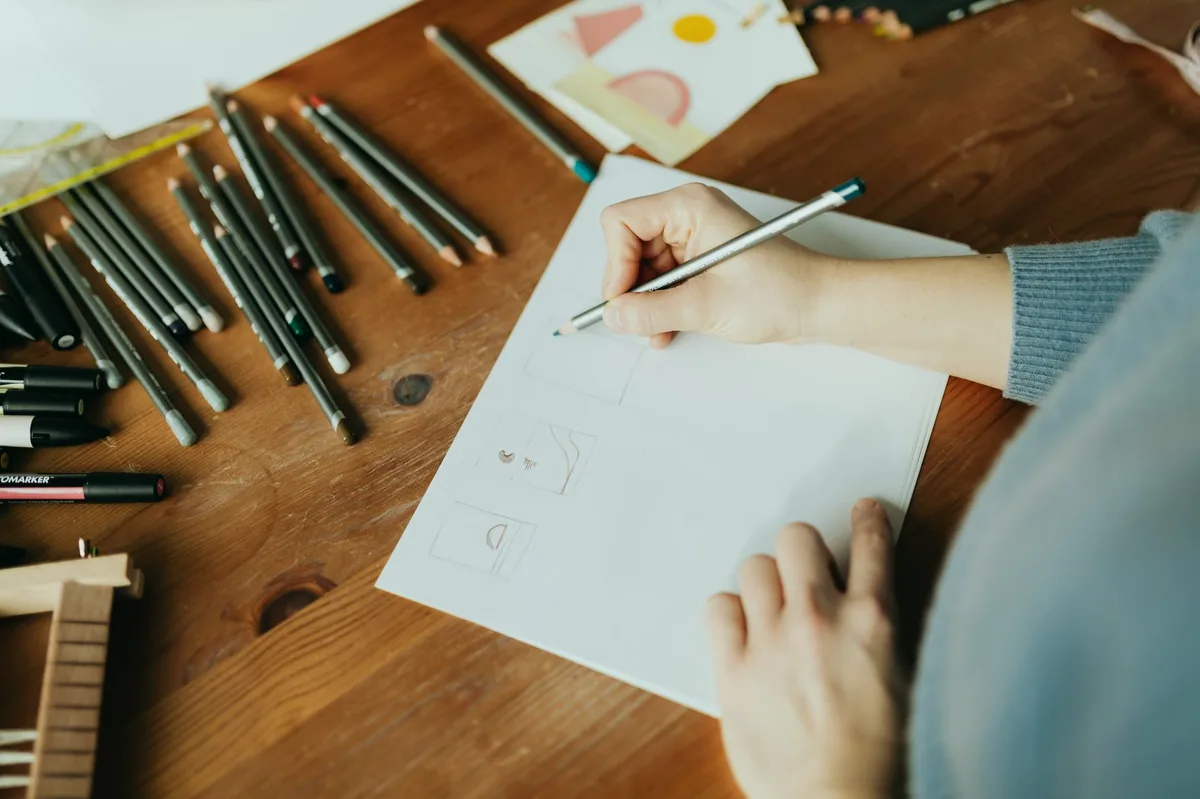 Masa başında çizim yapan kişinin elleri