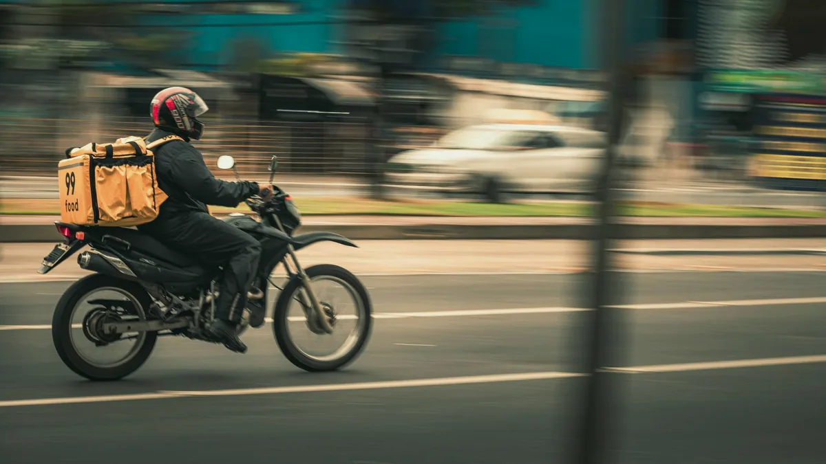 Şehir trafiğinde motosikletle teslimat yapan kurye