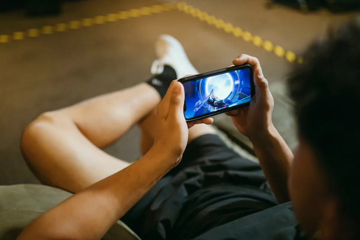 Telefonda mobil oyun oynayan genç
