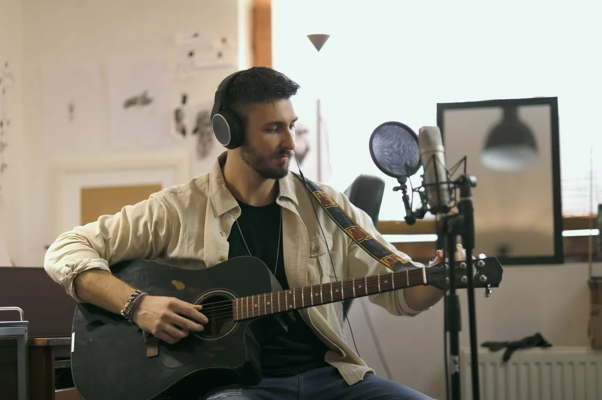Evde stüdyo kurulumunda gitarla kayıt yapan müzisyen