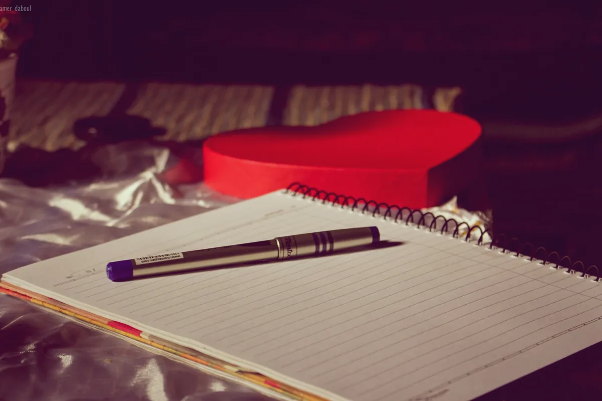Açık defter ve kalemle not alan el